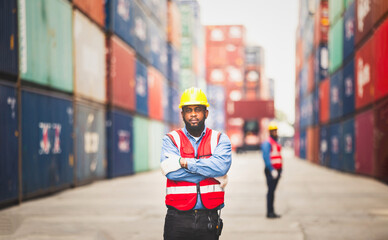 Portrait of African Engineer or foreman wears PPE checking container storage with cargo container background at sunset. Logistics global import or export shipping industrial concept.