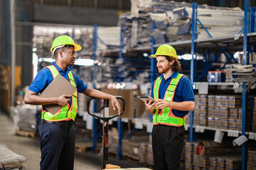 Foreman holds tablet and briefs new worker about the facility layout near pallet shelves.