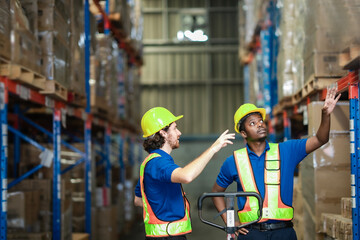 Coworkers push a cart and talk about work instructions, pointing towards shelves to guide logistics processes.