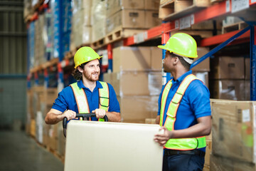 Box handlers discuss packaging tasks during a shift in a large industrial facility. In warehouse worker, logistic, fullfilment concept.