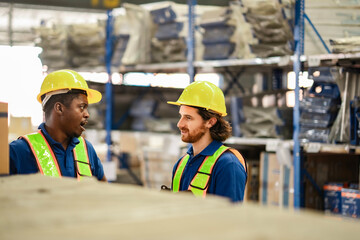 Two warehouse workers take a short break and chat casually in safety uniforms, enjoying a relaxed moment in the middle of a workday.