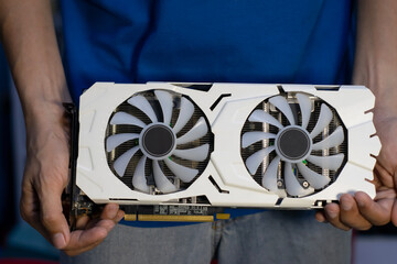 Front view of white graphics card, computer parts, technician holding graphics card
