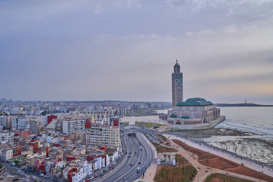 Aerial view of Hassan II Mosque with sprawling Casablanca cityscape. Iconic architecture by the ocean. Urban landscape blending modernity and tradition.