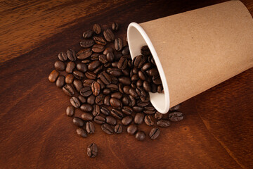 Disposable coffee glass with natural coffee beans on a wooden background