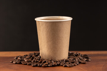 Disposable coffee glass with natural coffee beans on a black and wooden background