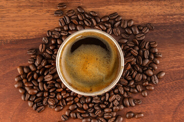 cup of coffee Seen from above with roasted natural coffee beans on a wooden surface