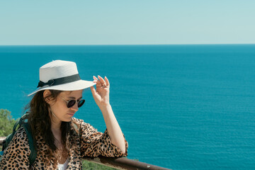 Fashion portrait. Smiling woman in fashionable look. Sea style. On blue background. Style and hot girl outdoor. Woman in sunglasses and straw hat.