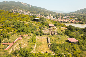 Panoramic aerial view of Armaziskhevi ruins with Mtskheta town, Svetitskhoveli Cathedral, and surrounding Caucasus hills in summer