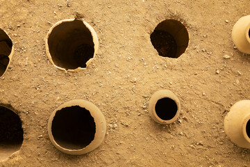 Clay wine vessels embedded in earth beneath wooden shelter at Armaziskhevi site, part of an ancient wine making cellar in Mtskheta region, Georgia