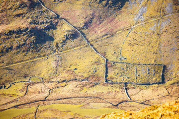 Aerial view of rectangular stone-walled Roman ruins in the hills of the Lake District National Park, England, with visible field boundaries and ancient infrastructure