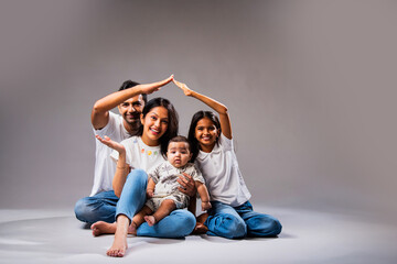 Asian family making roof with hands to express love, safety, and real estate investment values