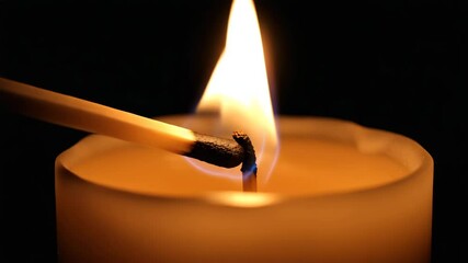Close up of burning match igniting candle isolated on black background. - Powered by Adobe