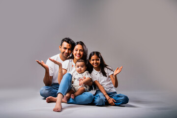 Spreading hands Indian family smiles happily, showing togetherness, connection on gray background