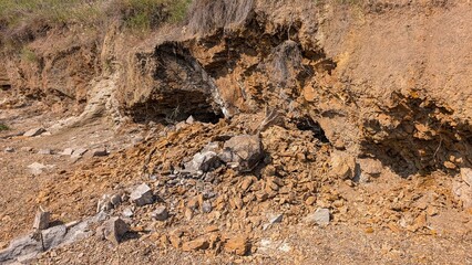 Massive landslide destroying hillside, revealing exposed rock layers, generating substantial debris field of rocks and sediment cascading downslope