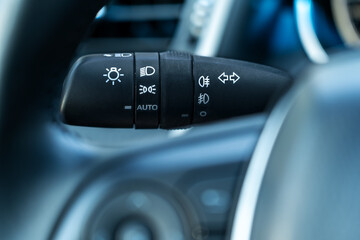 Close-up of a modern car&rsquo;s headlight and turn signal control lever on the steering column, showing auto lighting and fog light settings &mdash; automotive interior detail