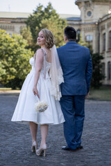 Naklejka premium Wedding day. Bride and groom holding hands. Happy young couple of newlyweds posing outdoors for photosession. Full body 