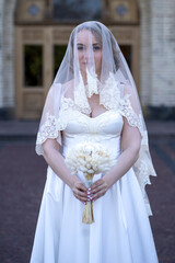 Bride have her face covered by a veil. Full length portrait of beautiful young bride in white short...