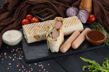 Hot dog in pita bread on a black background with sauce