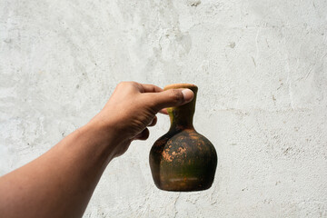Hand holding a mossy ceramic water jug