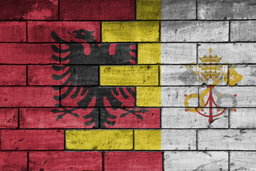 colourful painted big national flag of vatican city and flag of albania on a massive old brick wall background. concept
