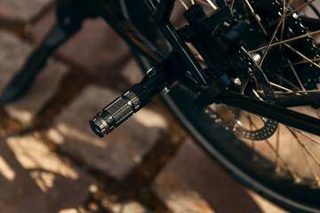 Top view closeup of parked black modern bicycle footrest on cobbled street.