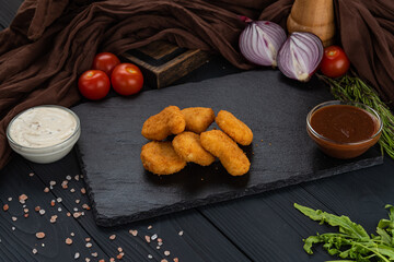 Nuggets on a black background with sauce