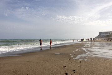  Foamy sea waves and relaxing people on the sandy beach of Bajondillo in Torremolinos, Malaga,...