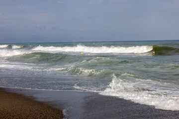 Foamy sea waves on the sandy beach of Bajondillo in Torremolinos, Malaga, Costa del Sol, Spain