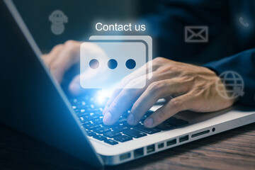 Businessman typing on laptop with "Contact Us" icon on screen. Concept of online communication, customer support, chatbot, and digital service connection.