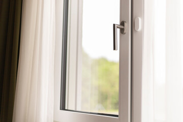 Bright sunlight streams through a stylish window with a sleek handle, illuminating the interior and...
