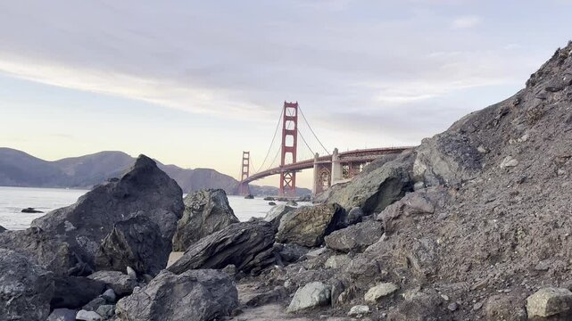 Waves crash at the beach in San Francisco, California with the Golden Gate Bridge in the background.