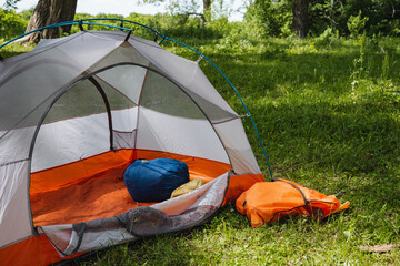 Experience the joy of setting up a cozy camping tent nestled harmoniously in a lush, vibrant green landscape, surrounded by the serenity of nature and a picturesque scenery that invites adventure