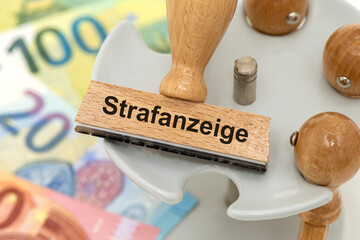 Ein Holzstempel ist beschriftet mit dem Aufdruck Strafanzeige