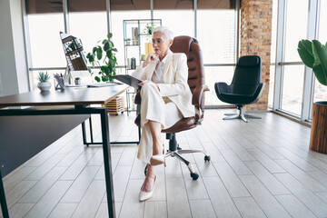 Professional mature businesswoman sitting in an elegant workspace, reflecting thoughtful strategy...