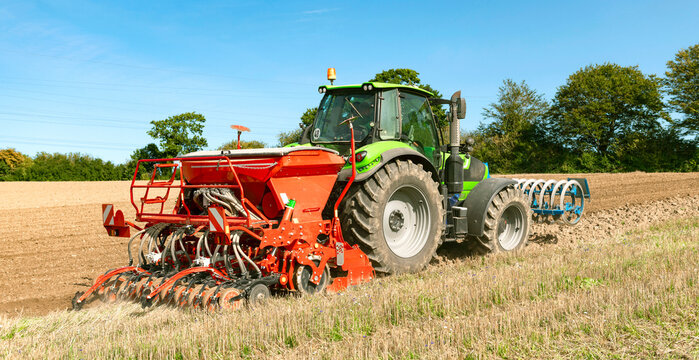 Tractor with seed drill, rotary harrow, and front packer tilling the field - 3592