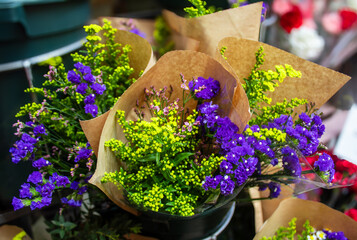 yellow and purple flowers in paper packaging in a flower shop