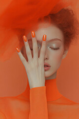 Vibrant style in orange monochrome: Close-up of woman with nails and makeup in warm tones, ideal for beauty, fashion and trends themes.