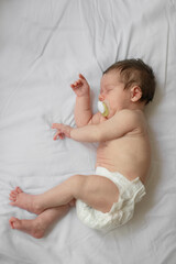Peaceful Sleeping Newborn Baby with Pacifier on White Bed