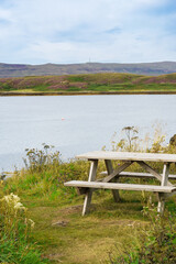 Wooden picnic table overlooking a peaceful lake in Scottish Highlands