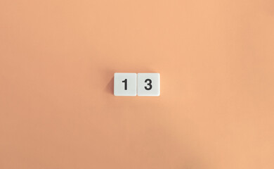 Number 13 on Minimal Letter Tiles Against Soft Pink Background