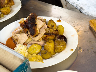 Roast pork with potatoes and sauerkraut on plate at outdoor market