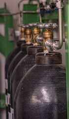 The photo shows a row of black metal compressed air cylinders connected to a system of pipes and valves. The cylinders are labeled "COMPRESSED AIR" and are used for technical purposes.