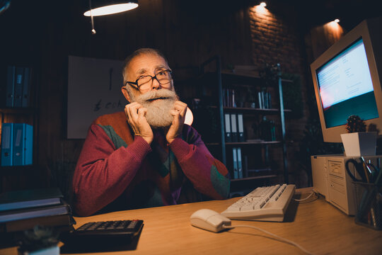 Elderly programmer working in a cozy home office environment, using vintage computer technology with a focused expression