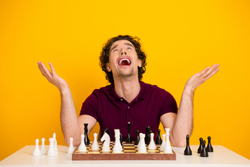 Joyful man celebrates chess victory in a bright yellow background while energetically gesturing at...