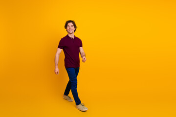 Fototapeta premium Casually dressed man walking confidently with a cheerful expression against a vibrant yellow background