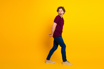 Cheerful young man in stylish outfit gesturing playfully over vibrant yellow background