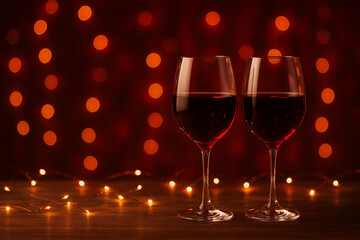 Romantic ambiance with red wine and glowing bokeh lights perfect for celebration.
