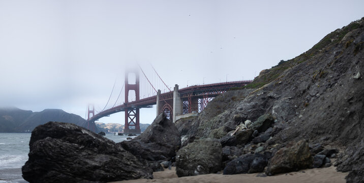 The Golden Gate Bridge in San Francisco, California disappears into the fog, as seen from the beach.