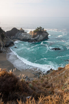 Iconic McWay Falls Cascading onto a Secluded Beach in a Turquoise Cove at Sunset in Big Sur, California