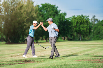 Senior Golfer and Young Golfer enjoying golf together at golf course, playing with fun in summer...